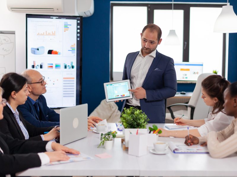 Company leadership explaining briefing project in conference room to team. Project leader discussing with teamworkers in broadroom, analysing charts, graphs, financial evolution of company.